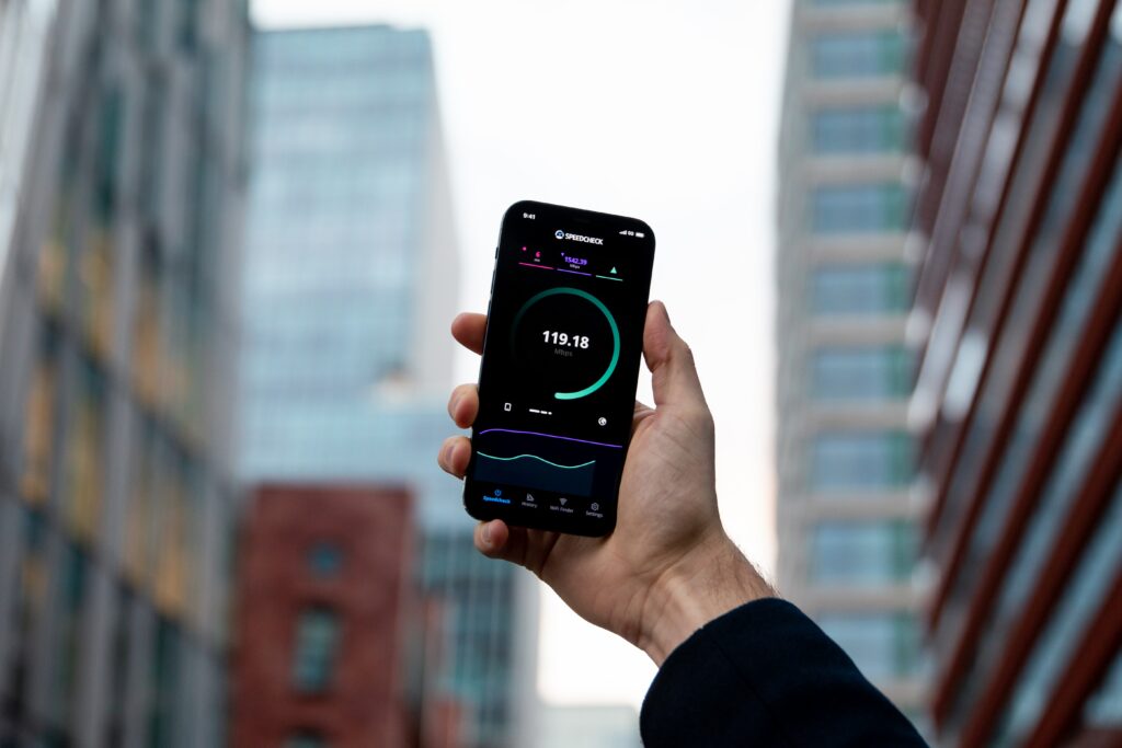 Eine Hand, die ein Smartphone hält, auf welchem gerade ein Speedcheck läuft.