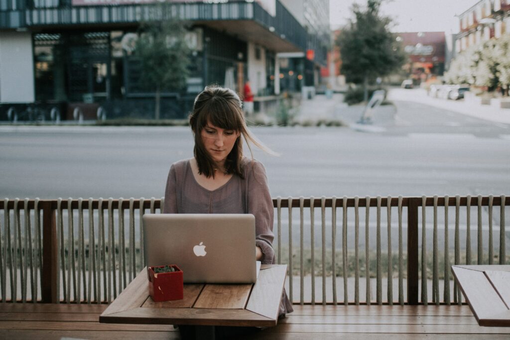 Femme travaillant à l'extérieur sur un ordinateur portable et connectée via le réseau mobile.