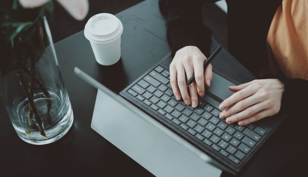 Frau mit Tablet, Smart Pen und Keyboard Folio am Arbeiten an einem Tisch in einem Cafe